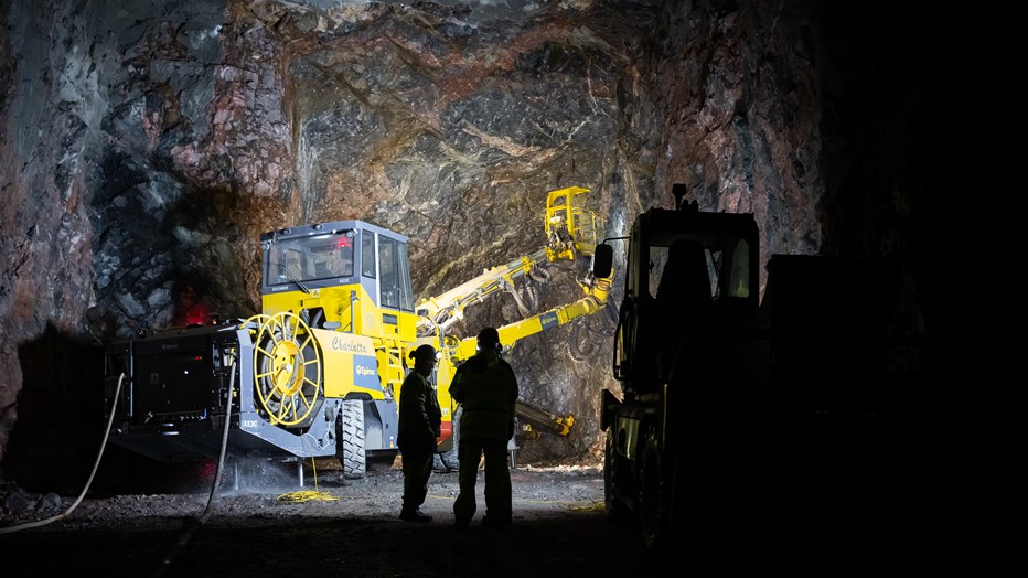 The subway to Nacka is being built using traditional tunneling methods, which involve drilling, loading, and blasting. The drilling rig Charlotta in a tunnel. Workers in the foreground.