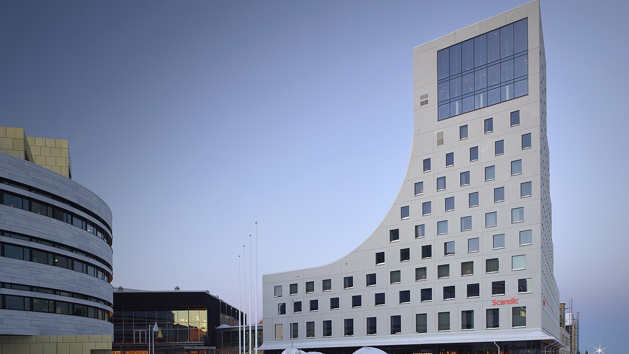 Framsida av det vita hotellet mot ljusblå himmel. Sidorna på hotellet är inspirerade av Kebnekaise med en jämn och en ojämn siluett.
