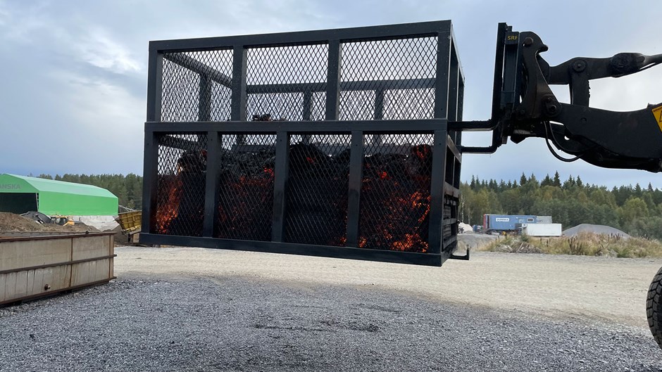 En korg med glödande kol flyttas med en truck.