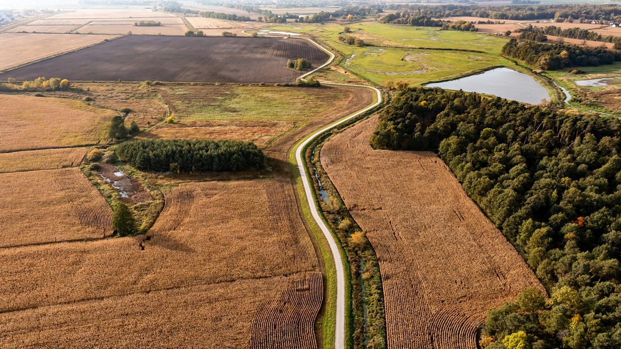 Flygbild med en väg som skär rakt igenom landskapet.