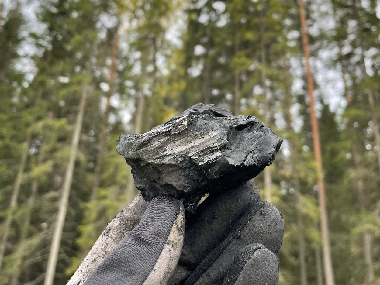 En större bit fast biokol som hålls av en behandskad hand.