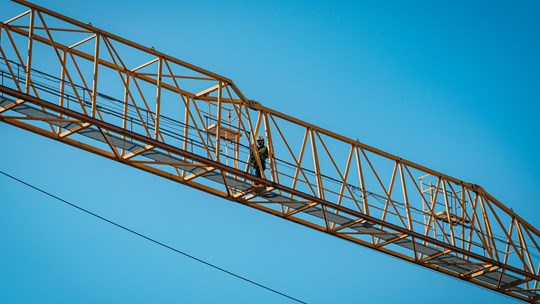 Byggarbetare jobbar högt upp i en lyftkran.