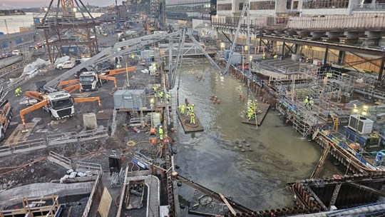 Bilden visar en byggarbetsplats med människor och maskiner.