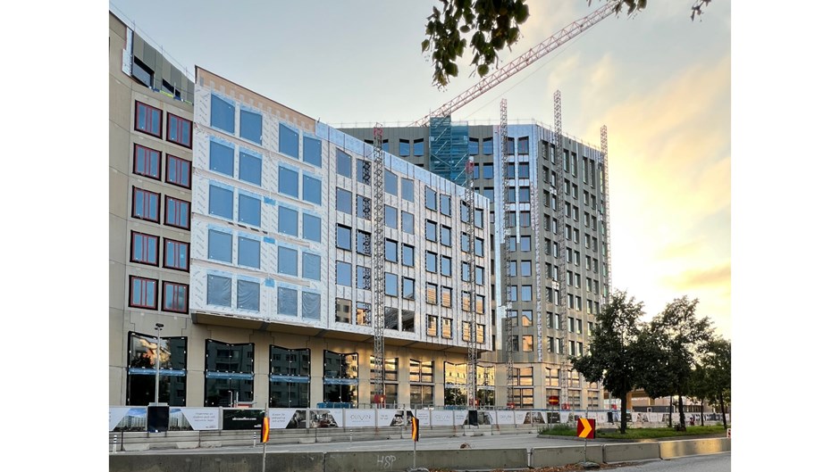 Solen speglar sig i fönstren på byggprojektet Olivin i Stockholm.
