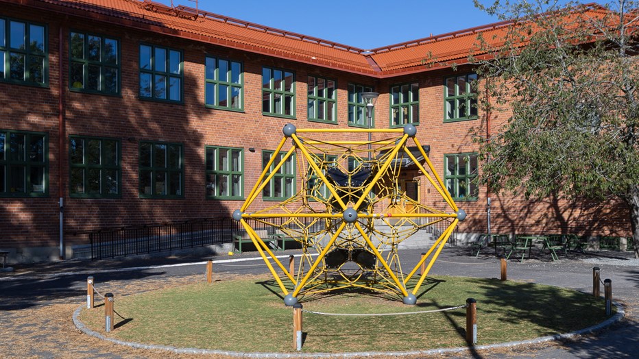 Den gula klätterställningen är en färgklick på skolgården. På skolgården finns en gul klätterställning.