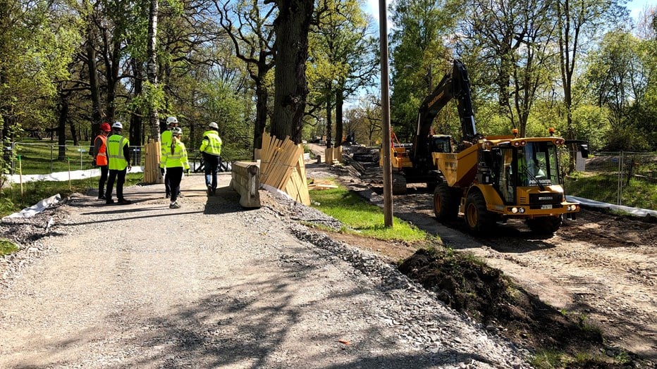 Skanska was awarded a construction contract to carry out the project together with Ellevio.  Construction workers on a gravel path, next to trees and an excavator.