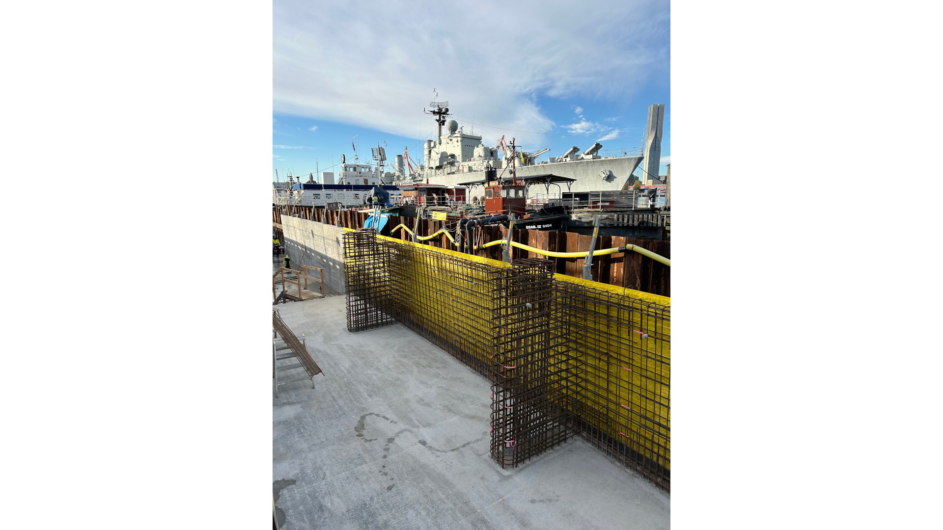 Armeringskorgar placerade framför spontvägg vid Packhuskajen med fartyg och arbetsplattformar i bakgrunden.