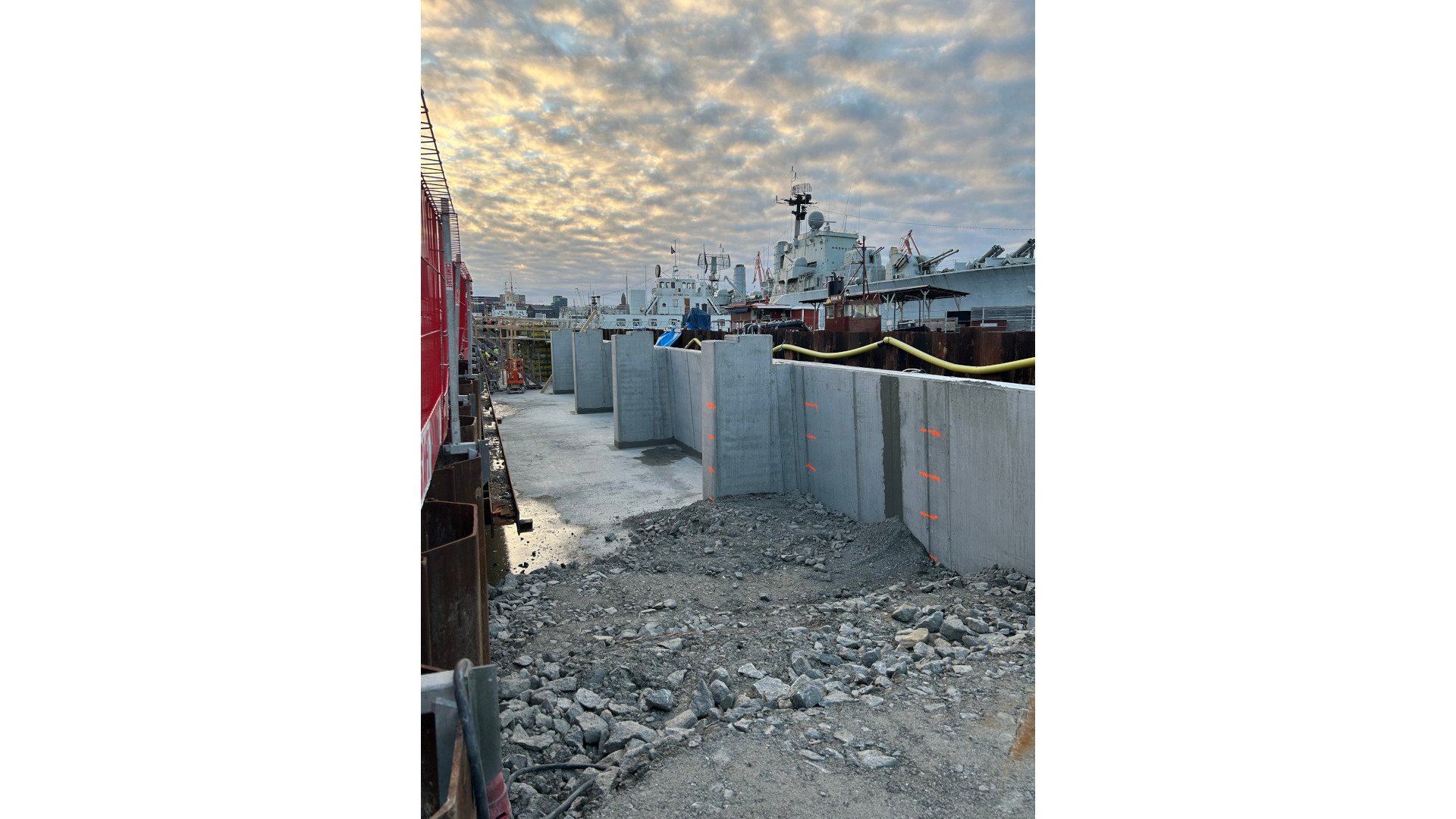 Rader av nygjutna betongväggar framför spontvägg vid Packhuskajen med stenfyllning i förgrunden.