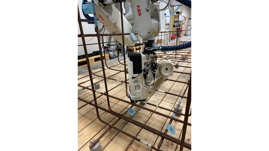 En robotarm jobbar med att fästa ett armeringsjärn.