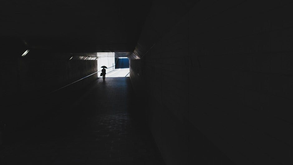 En person går i en mörk gångtunnel.