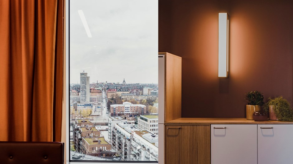 Genom ett fönster har man utsikt över Stockholm. Inredningsdetalj i varma jordtoner.