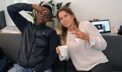 Ung kille med keps sitter på en soffa tillsammans med Skanskas vice vd Alexandra Laurén som är en av mentorerna.